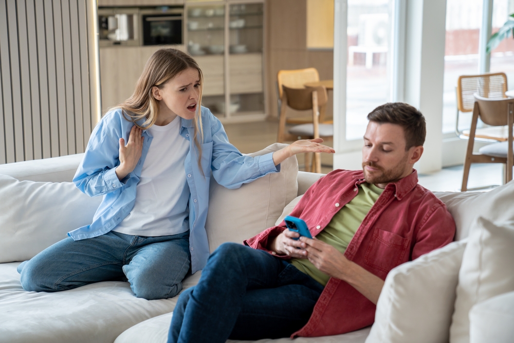 Indifferent,Ignoring,Man,Sits,On,Sofa,With,Mobile,Phone,,Playing